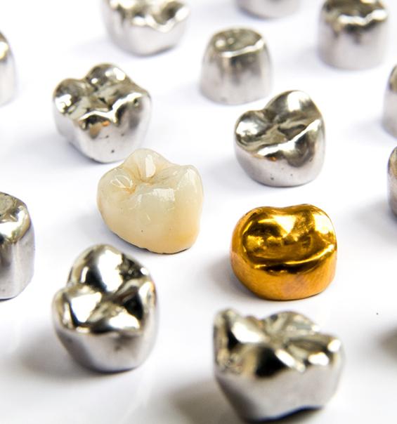 Several dental crowns of various materials on white surface