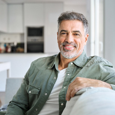 Senior man smiling while sitting on couch