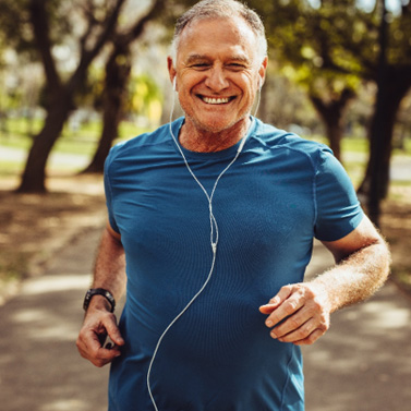 Senior man smiling while jogging outside